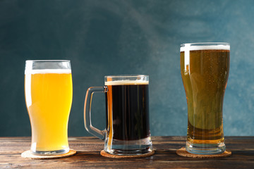 Different mugs with beer on wooden table, copy space