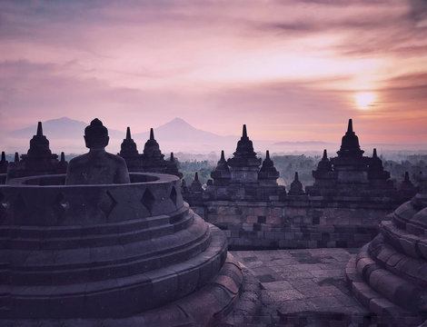 buddha statue and borobudur temple at colorful sunrise
