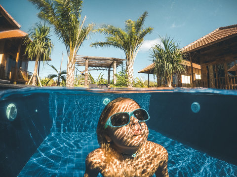 young boy diving with sunglasses in a pool from a tropical resort