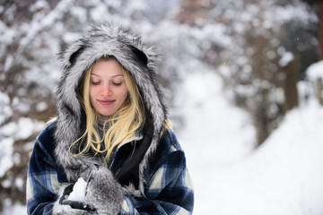 Girl playing with snow. Season of winter. Wintertime. Smiling woman in warm clothing with snowball. Beautiful young woman in winter. Girl in mittens hold snowball. Happy woman holds snowball in hands.