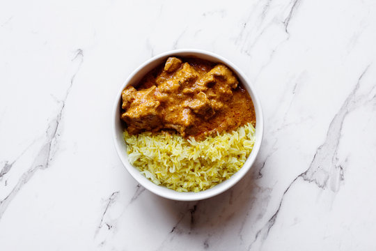 Indian curry with rice, in a white bowl on marble background