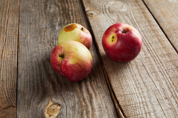 apples with rotten spot on brown wooden surface