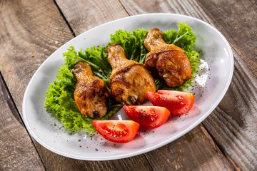 Fried chicken drumsticks with vegetables on wooden table