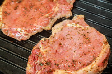 Cooking pieces of pork with spices on the grill pan.
