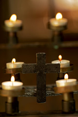 christian cross in front of burning candles in a chappel