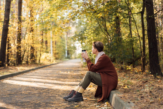 Woman drinking hot beverage in autumn park