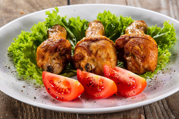 Fried chicken drumsticks with vegetables on wooden table
