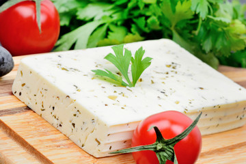 Cheese with herbs and tomatoes on cutting board