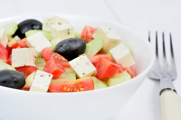 Vegetables salad with cheese in a bowl on wooden table