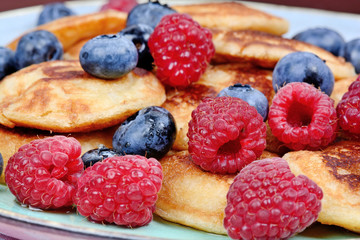 Small pancakes with berries and agave syrup in a plate