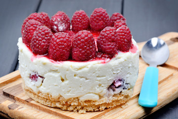 Mini cheesecake with white chocolate and raspberries on cutting board