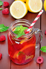 Raspberries lemonade in a jar on a wooden table