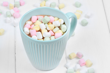 Hot chocolate with colorful marshmallows in a cup on a wood table
