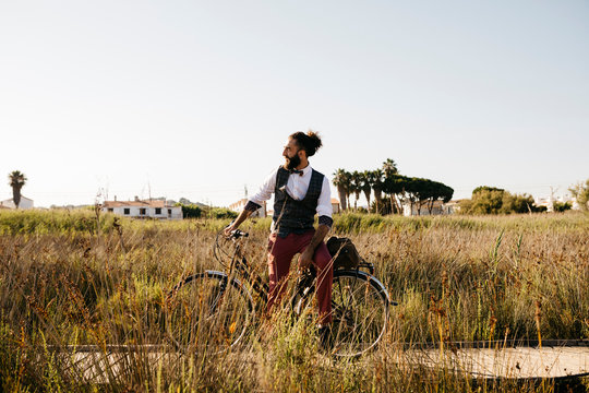 Well dressed man with his bike on a wooden walkway in the countryside having a break
