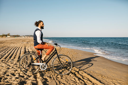 Well dressed man with his bike on a beach