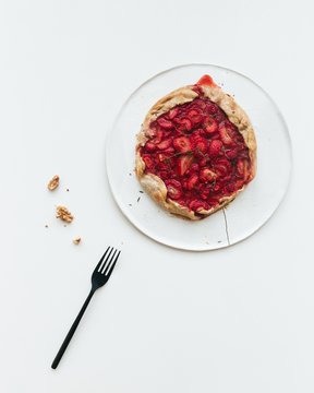 Delicious fresh baked vegan strawberry galette with walnuts on white ceramic plate