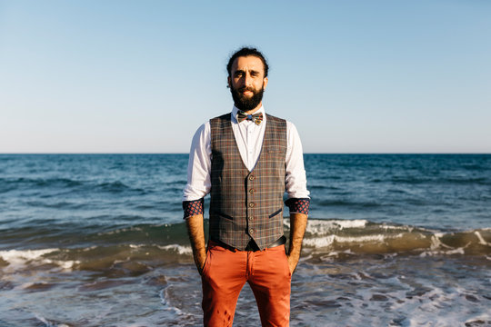 Portrait of a well dressed man standing on a beach at water's edge