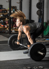 Fototapeta na wymiar Young, strong woman weight lifter lifting heavy barbell.
