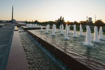 Fototapeta na wymiar Evening Wide View of Victory Park/Park Pobedy and its fountains on Poklonnaya Hill. The city becomes calm and quiet at sunset. High angle view.