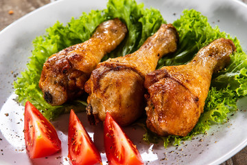 Fried chicken drumsticks with vegetables on wooden table