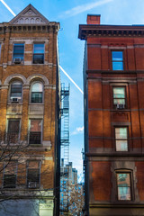 Two typical brownstone buildings against a beautiful blue summer sky in Harlem, New York, NYC, USA