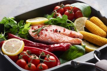 raw salmon steak with spices, vegetables and greenery in grill pan
