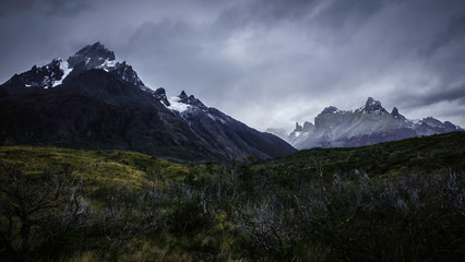 Fototapeta na wymiar Torres del Paine trail. On the right is the ‘Paine Grande’ mountain. Below, you can see many wild vegetation an snowy peaks. Patagonia, Chile