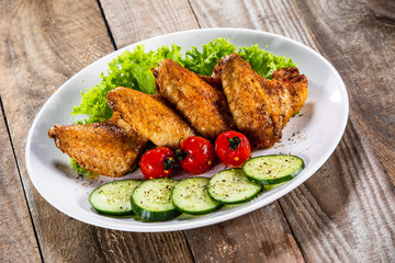 Grilled chicken wings with vegetables on white plate