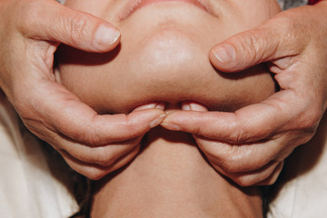 Fototapeta premium spa specialist is doing facial massage to a young girl in a medical cap. beauty treatments close-up