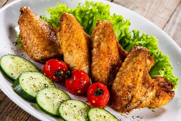 Grilled chicken wings with vegetables on white plate
