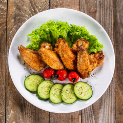 Grilled chicken wings with vegetables on white plate