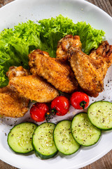 Grilled chicken wings with vegetables on white plate
