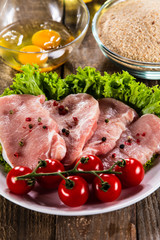 Raw pork chops and vegetables on white plate 