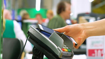 person pays using smartphone and terminal in supermarket