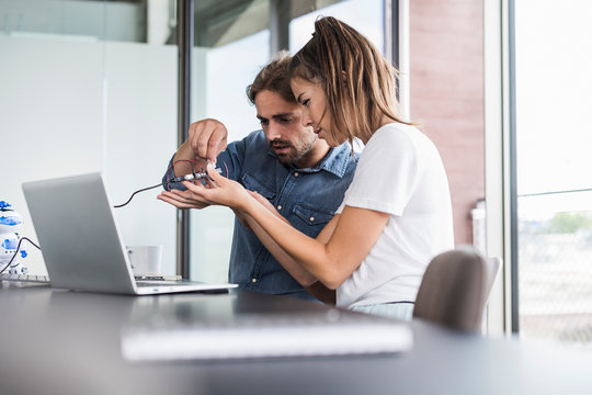 Young woman and man working on computer equipment in office