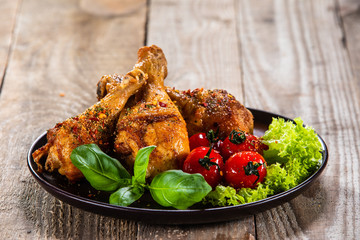 Fried chicken drumsticks with vegetables on wooden table