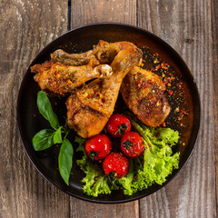 Fried chicken drumsticks with vegetables on wooden table