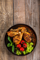 Fried chicken drumsticks with vegetables on wooden table