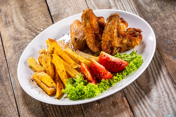 Grilled chicken wings, chips and vegetables
