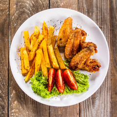 Grilled chicken wings, chips and vegetables