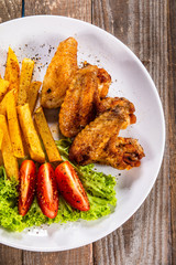 Grilled chicken wings, chips and vegetables