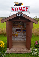 Fototapeta na wymiar Honor system rural honey stand in field on Prince Edward Island Canada.
