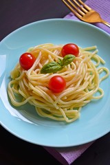 Delicious spaghetti with herbs and tomatoes on a black background.