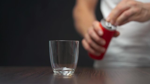 Man opening red soda can and filling glass with sugar. Consumption of sugary beverages.