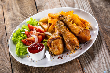 Grilled chicken drumsticks with baked potatoes and vegetables