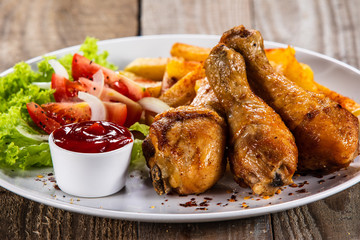 Grilled chicken drumsticks with baked potatoes and vegetables