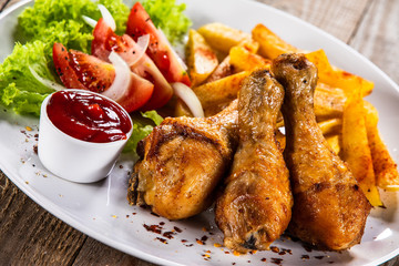 Grilled chicken drumsticks with baked potatoes and vegetables