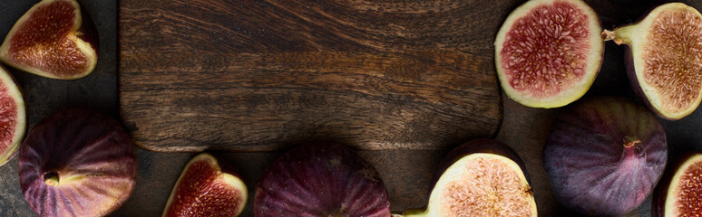 panoramic shot of ripe figs around empty wooden cutting board on stone background