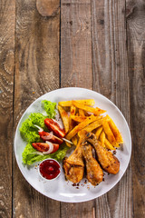 Grilled chicken drumsticks with baked potatoes and vegetables