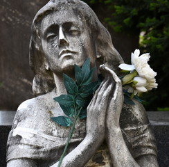 Mit geschlossenen Augen trauernde Frau mit Blume in den Händen